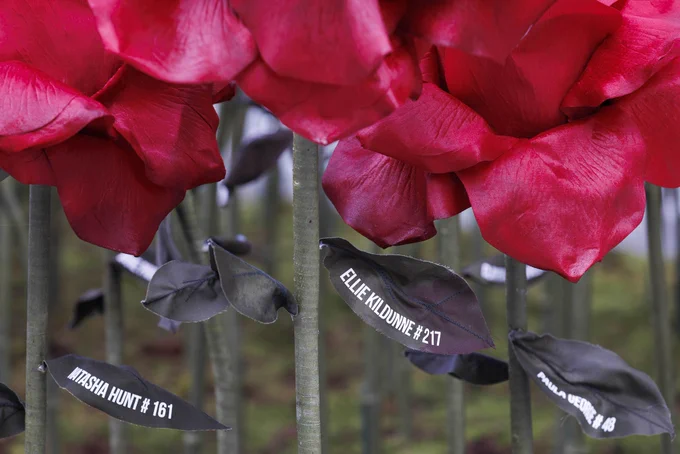Three handmade red roses with players’ names and legacy numbers written on the leaves.