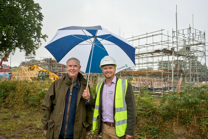 Photo of Sir Geoffrey Cox and Westward Housing's CEO standing under an umbrella