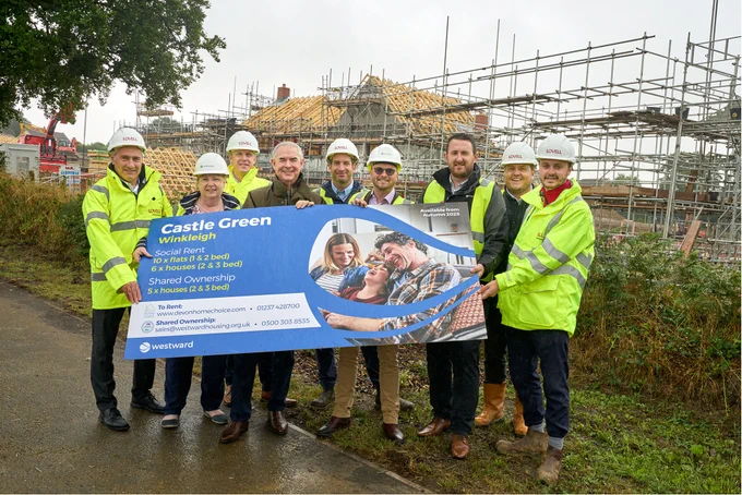 Image of 9 people holding a sign up for a new housing development