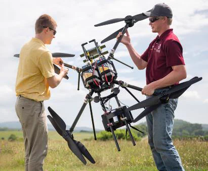 two men are holding a large drone 