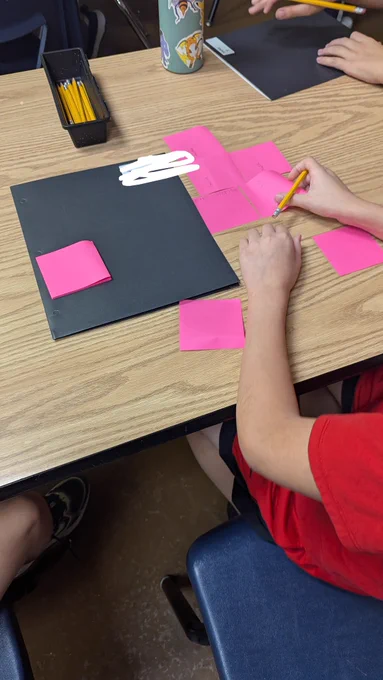 Students writing on pink post it notes