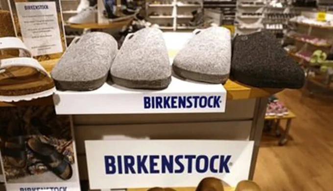 Display of Birkenstock clogs in a retail store with multiple color options arranged on a shelf labeled Birkenstock.