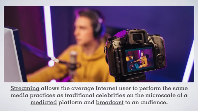 Camera shooting an esport athlete streaming his gameplay in front of a computer on a PowerPoint slide with the text: Streaming allows the average Internet user to perform the same media practices as traditional celebrities on the microscale of a mediated platform and broadcast to an audience.