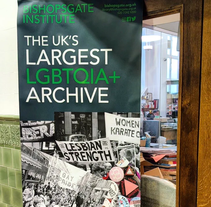 A banner outside a wooden doorway reading Bishopsgate Institute: The UK's largest LGBTQIA  archive.