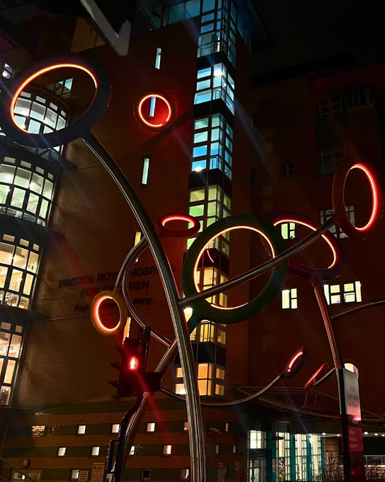 The hoops of the Lollipop Be-Bop sculpture outside Bristol Royal Hospital for Children are lit up in an orange light.