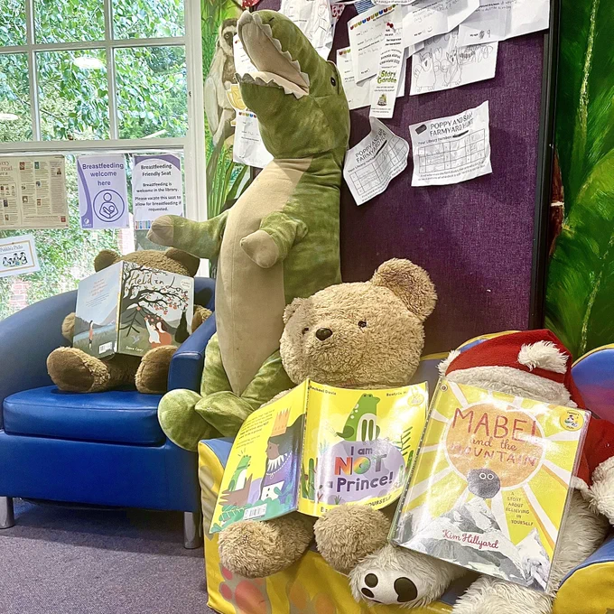 Photograph of teddy bears and a dinosaur soft toy with books at Farnham Library. 