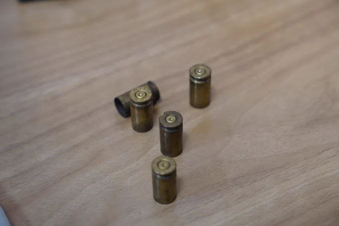 Close-up of five spent brass bullet casings lying on a wooden surface.