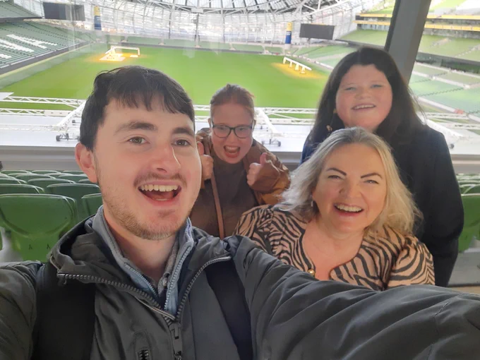 Four people taking a selfie with the view of an empty Aviva Stadium behind them. 