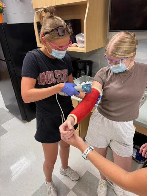 2 third year ot students practicing with the saw to saw off the casting during lab