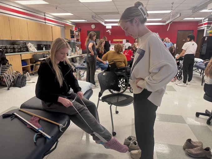 2 second year ot students using an adaptive equipment during lab