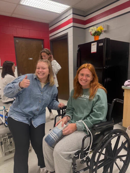 2 second year ot students posing for picture with an adaptive tool during lab