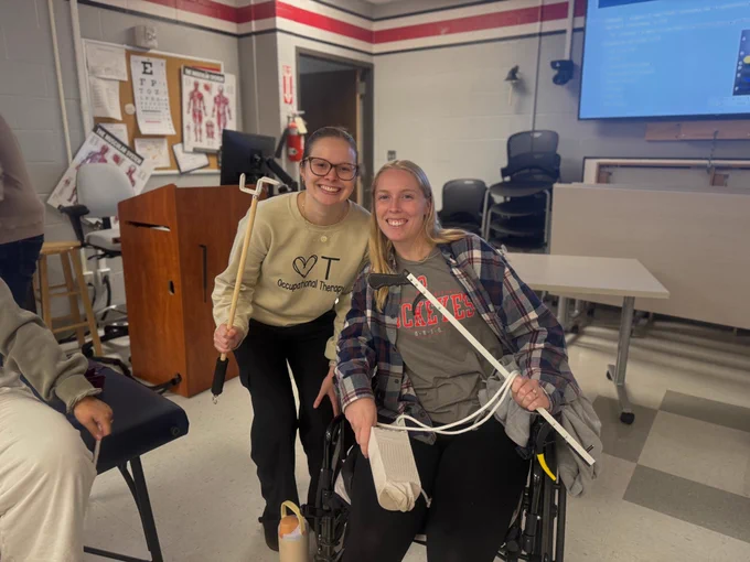 2 second year ot students posing with different adaptive equipments 