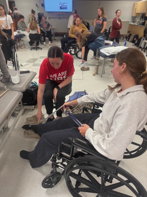 2 second year ot students practicing with an adaptive equipment