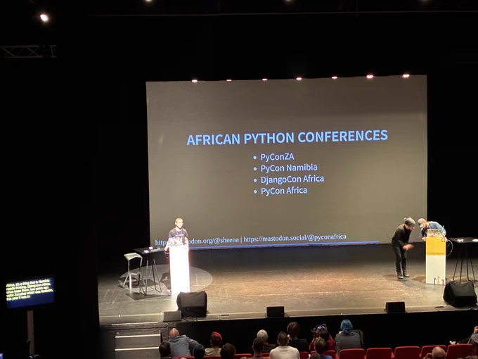 Sheena on stage with a list of African Python conferences: PyConZA, PyCon Namibia, DjangoCon Africa, PyCon Africa
