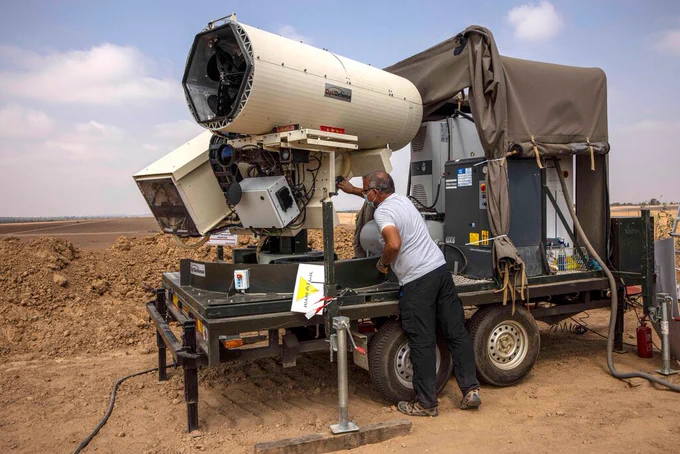 An Israeli police officer demonstrates a laser defense system near the Israel-Gaza border in 2020.Credit...Tsafrir Abayov/Associated Press