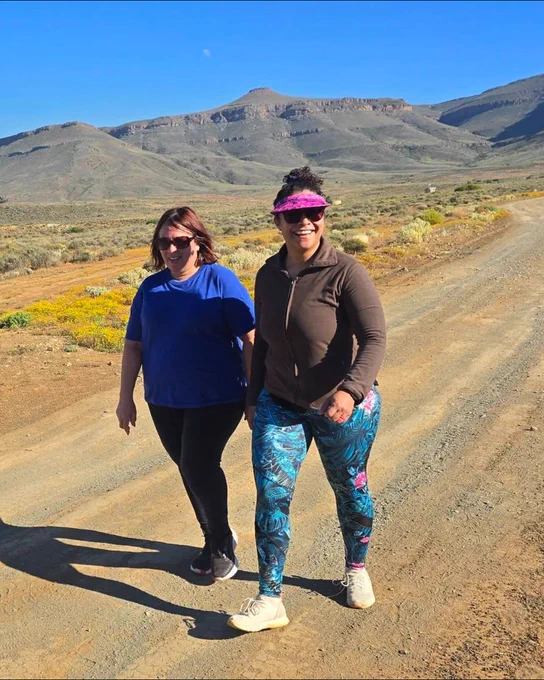 Two parkrunners walking with mountains in the background.