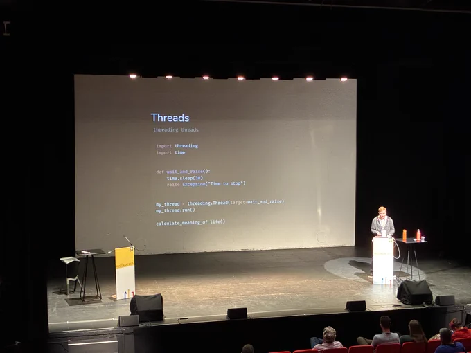 Jake on stage with a slide about threads