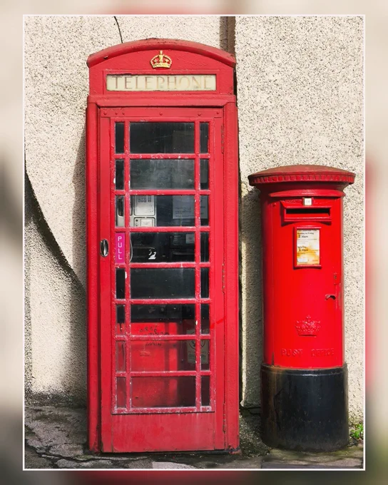 Rote Telefonzelle und roter Briefkasten.