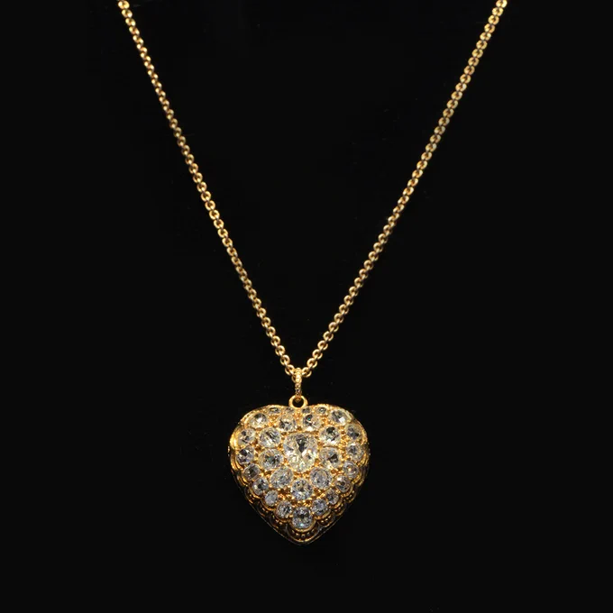 A gold chain necklace featuring a heart-shaped pendant set with dozens of sparkling diamonds.