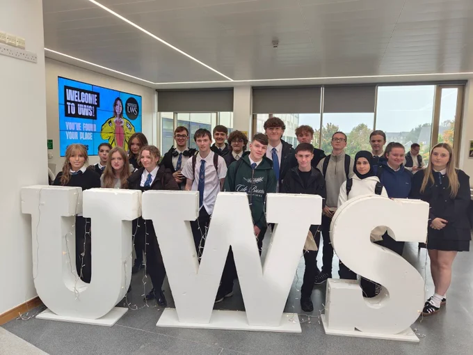 Group of students standing behind large 'UWS' letters at the University of the West of Scotland.