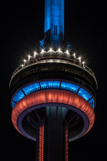 Closeup of the #CNTower at night lit blue and red / Gros plan de la #TourCN illuminée en rouge et bleu la nuit. 