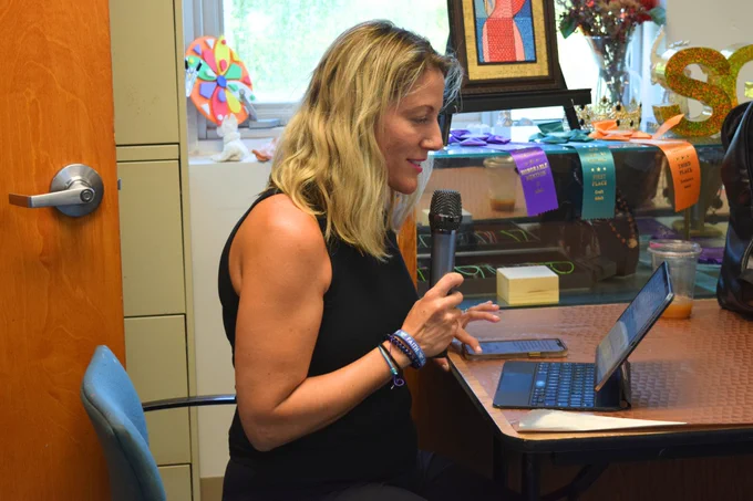 A meditation teacher speaks into a microphone during her session at Miami Lighthouse for their senior participants.