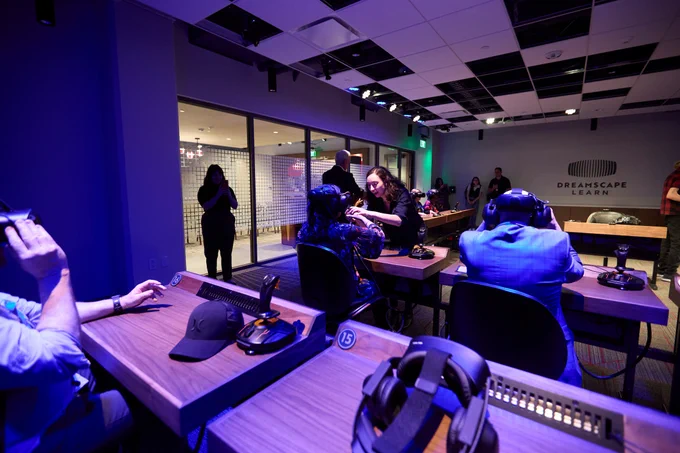 Participants engage with virtual reality equipment at a Dreamscape Learn facility.