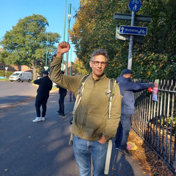 A photograph of a man holding up a fist on the street
