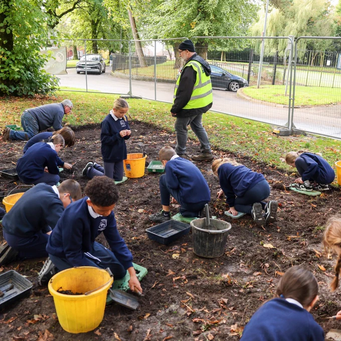 Image shows school pupils taking part in the archaeological dig in Woodvale Park with the team from the Community Archaeology Programme NI (CAPNI).