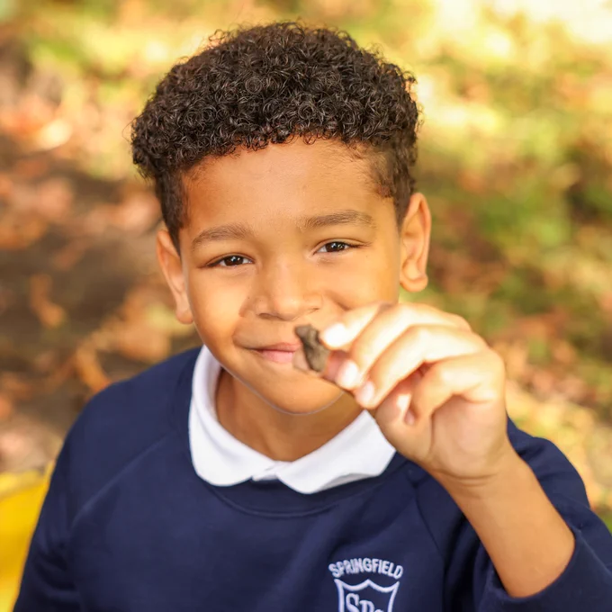 Image shows a student holding an artefact that was found during the dig.