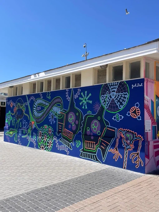 Happy to share that the completion of this wonderful science - art initiative. This mural aims to bring phytoplankton out of obscurity, anchoring them in public consciousness as vital agents of planetary health and climate stability.

Ocean Drifters: The Invisible Forest
By Joh Del

This mural celebrates the hidden world of phytoplankton - tiny, single-celled organisms that drift in our oceans and sustain life on Earth. Though invisible to the naked eye, these microscopic plants use photosynthesis to produce roughly half of the planet’s oxygen. They also absorb vast amounts of carbon dioxide out of the atmosphere, helping to lessen the impacts of climate change. As the base of marine food webs, phytoplankton also support fish, marine mammals, and ultimately human food security. Their unseen beauty and essential role in regulating the planet's climate and ecosystems are brought to life here through vibrant forms and flowing patterns.

Find it on display at the Sea Point Promenade in CT