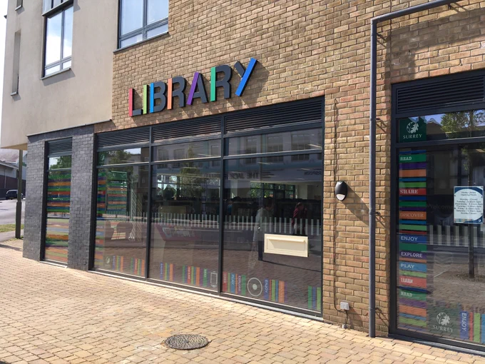 Photo of the outside of a library building - there are a row of large windows and above these are colouring lettering spelling out "LIBRARY"