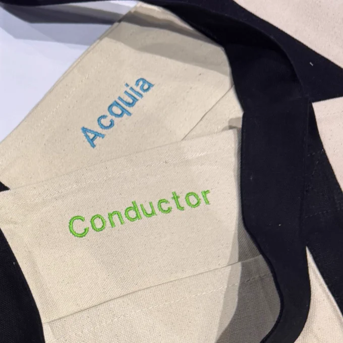Two custom tote bags with Acquia and Conductor's logos on each bag.
