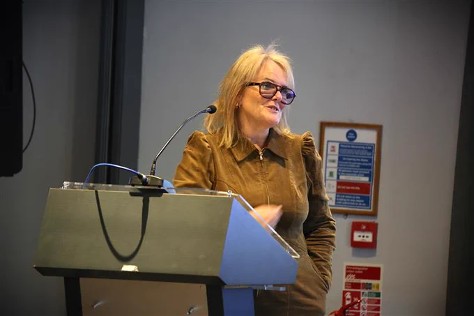 Photo of Di Hull, brown dress, blonde hair, glasses