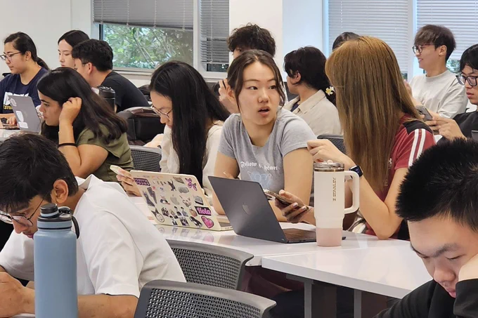 Students sitting at desks engaged in a discussion during AI.Xperience. 