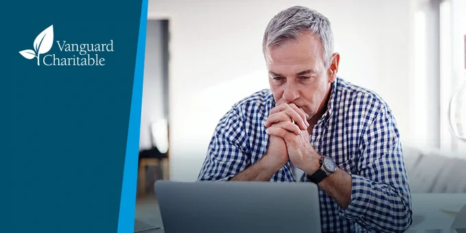 Older white gentleman sitting in front of a laptop looking concerned. 