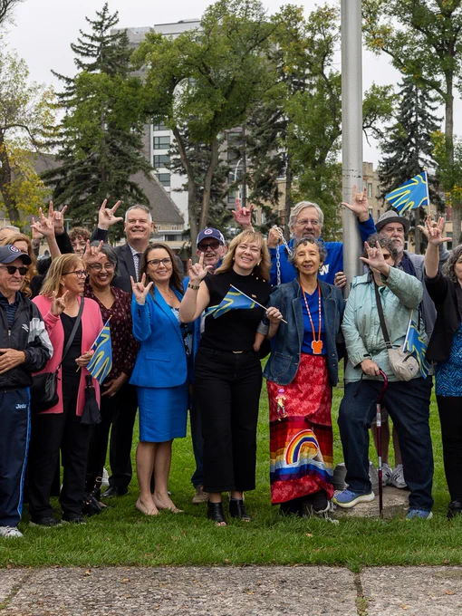 Group of Manitobans holding Deaf flag signing "I love you"