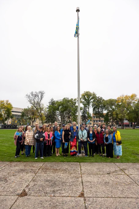 Group of Manitobans in front of the Deaf flag raised at Memorial Park.