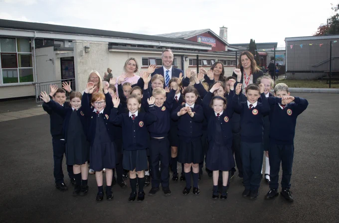 Education Minister, Paul Givan pictured with staff and pupils at Holy Child Primary School