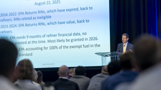 A person presenting at a conference with a PowerPoint slide about EPA regulations, viewed from behind the audience.