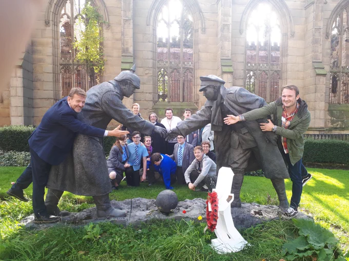 Baby slink at the ‘bombed our Church ‘ Liverpool with Great War statues depicting German and British troops  shaking hands from 1914 Christmas truce football match
