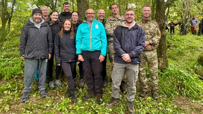 Nine people with two Royal Marines Reservists in a forest.