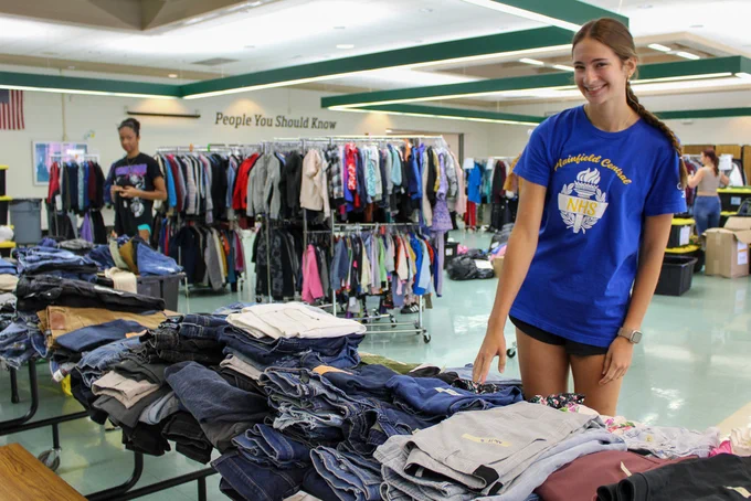 student standing by piles of pants