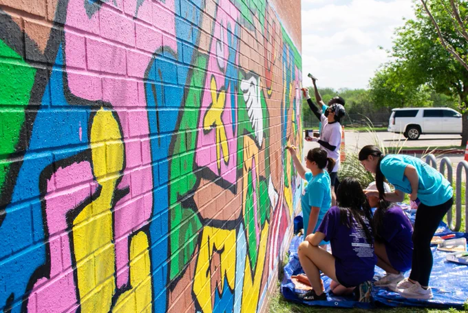 Student volunteers paining a mural