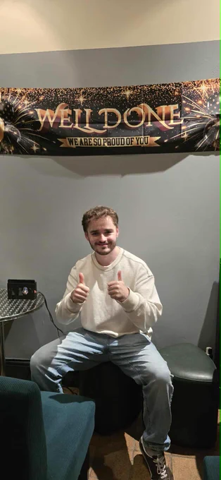 Red sat below a "Well Done, we are so proud of you" banner, Red also has both of his thumbs up and a smile on his face, what a guy