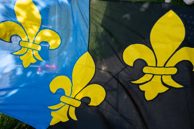 The flag of Monmouthshire, half blue and half black with three gold fleurs-de-lys symbols.