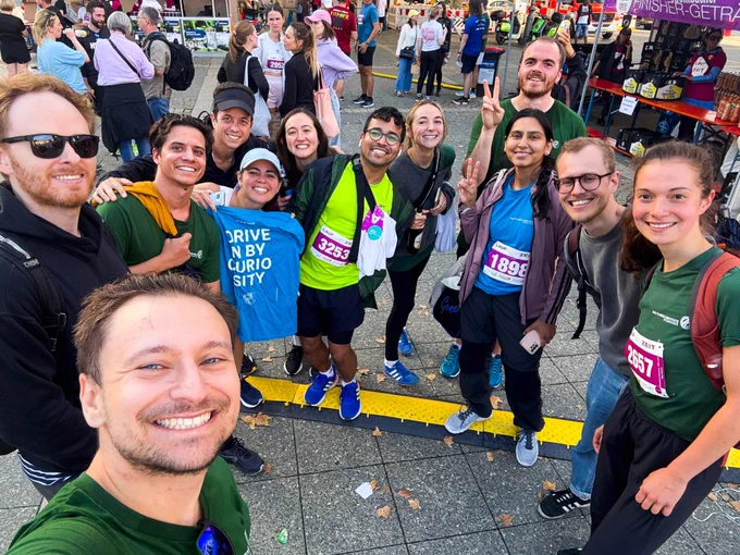A diverse group of young people in running gear smile for the camera.