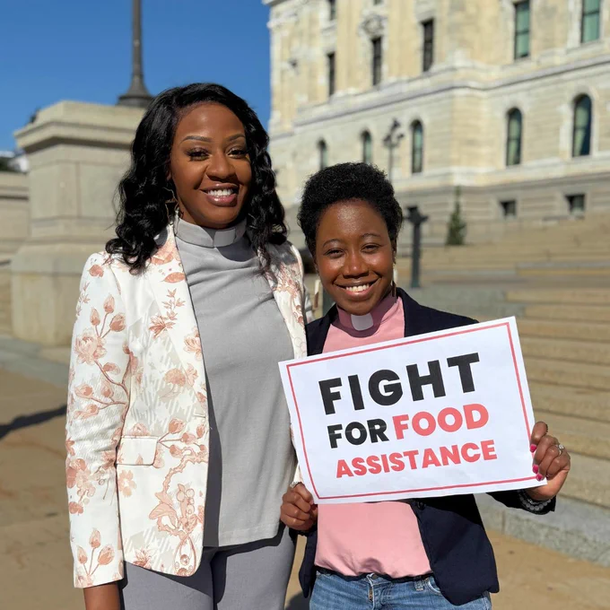 Photo shows two clergy members holding sign that says: "Fight for food assistance"