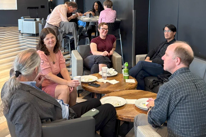 5 WLUFA Members sitting around a few table smiling and chatting with each other.