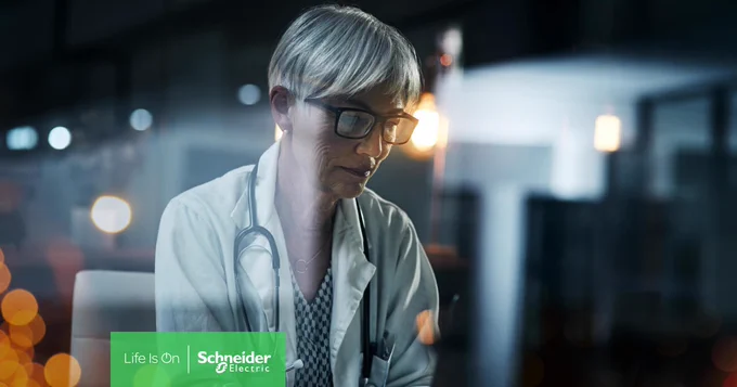 Eine Frau mit Brille und Arztkittel blickt konzentriert auf einen Bildschirm. Um ihren Hals hängt ein Stethoskop.